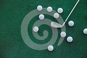 Golf club and ball on a green lawn. top view of the golf club and balls lying on the artificial lawn.