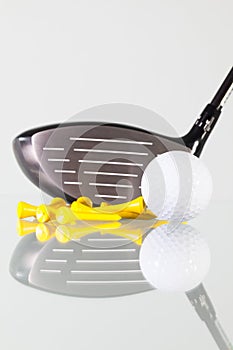 Golf club,ball and yellow tees on a glass table