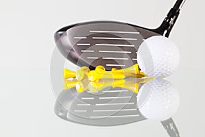 Golf club,ball and yellow tees on a glass table