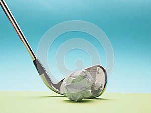 Golf club with a crumpled paper ball as golf ball