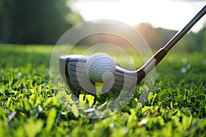 Golf club and golf ball close up in grass field with sunset