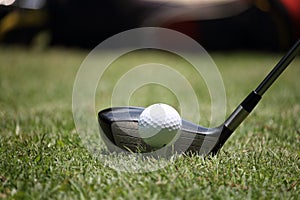 Golf club and golf ball close up in grass field with sunset. Gol