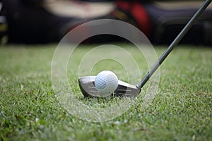 Golf club and golf ball close up in grass field with sunset. Gol