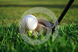 Golf club and golf ball close up in grass field with sunset. Golf ball close up in golf coures at Thailand