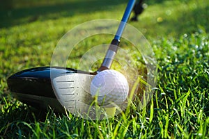 Golf club and golf ball close up in grass field with sunset. Golf ball close up in golf coures at Thailand