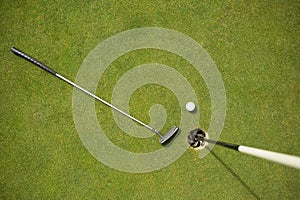 Golf club and golf ball on the putting green beside flag