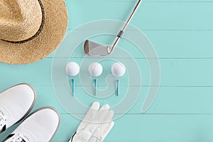 Golf club, golf balls, Golf shoes and tees on a wooden surface in turquoise, top view, copy space