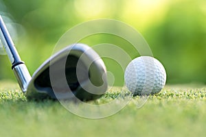 Golf club hitting golf ball along fairway towards green with copy space, green nature background.