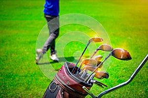 Golf club suit in bag cart and blurred golfer hitting golf ball