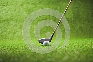 Golf club and white ball on green grass