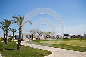 Golf clubhouse with palm trees, buggies and putting green in Spain