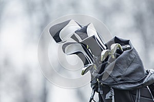 Golf clubs in a bag on a cart on a golf course.