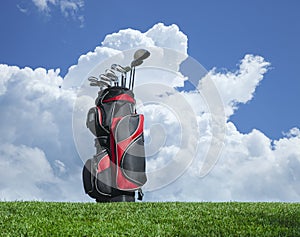 Golf clubs on grass with blue sky and clouds
