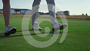 Golf couple legs going walk on course grass. Two rich people stroll country club