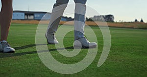 Golf couple legs going walk on course grass. Two rich people stroll country club