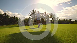 Golf course and champion player near the hole with flag, luxury tropical resort