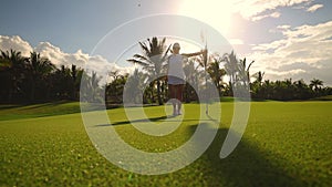 Golf course and champion player near the hole with flag, luxury tropical resort