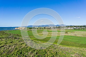 Golf course on the cliffs of the pacific ocean coast, resort and villas in the background, Half Moon Bay, California