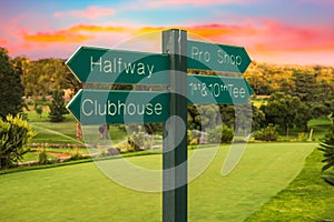 Golf course direction signs on fairway and colourful sunset