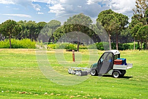 Golf course and golf cart collecting golf balls. Ballpicker on driving range of golf club