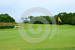 Golf course green and fairway with yellow flag with water trap in central Florida