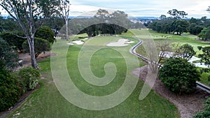 Golf course green with flag, bunkers, dam and tree lined fairway