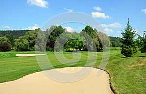 Golf course, green grass, large sand pit, trees