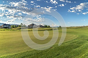 Golf course and homes with blue sky and puffy clouds overhead on a sunny day