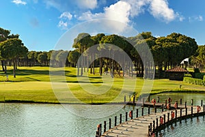 Golf course with a lake and a bridge, on a sunny day with a beautiful sky