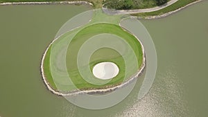 Golf course and lake landscape from flying drone. Aerial view green golf course on island in pond in golfing club.