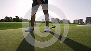 Golf course. A man pushes a golf ball with a club