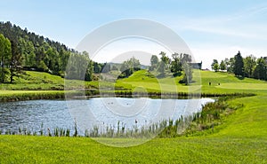 Golf course with pond, blue sky and green nature