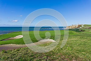Golf course putting green on the cliffs by the pacific ocean, Resort in the background, Half Moon Bay, California