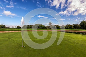 Golf course putting green under blue cloudy sky