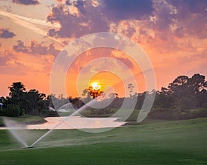 Golf course sunset with sprinklers in the sunset