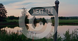 Golf course tee sign in empty golfing park. Show direction on sunset nature lake