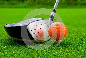 Golf driver with orange ball.