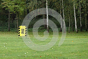 Golf driving range, impact point 50 meters. Number fifty on a yellow poster