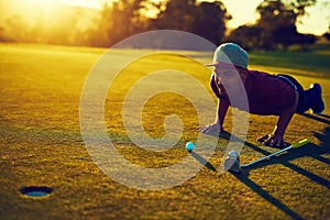 Golf is a full body experience. a young man eyeing up the putt during a round of golf.