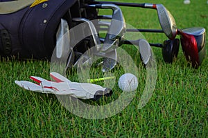 Golf glove , white golf ball and tee put on green grass of golf course ,This golf objects for play