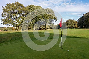 Golf green with ball and red flag on Chorleywood Common