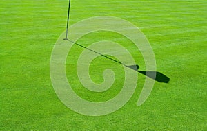 Golf green and a flag shadow