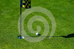 Golf hole. Golf ball on lip of cup on grass background.