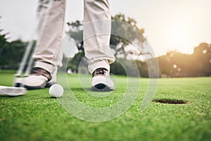 Golf, hole and legs of athlete or player hit ball and professional golfer training and putting on a filed as exercise or