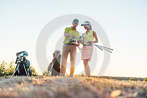 Golf instructor teaching a young woman how to use different golf clubs