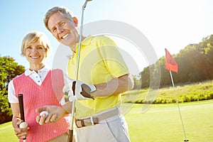 Golf keeps us bonding regularly. Elderly couple holding their golf clubs and balls on the green.