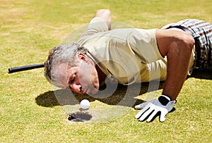 Golf, man and blowing ball into hole on a grass field for player match and putting. Fitness, sport and funny mature male