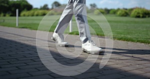 Golf man legs walking at course. Luxury man going at summer golfing country club