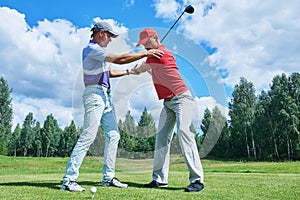 Golf training. Instructor trains new player in summer