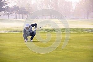 Golf player on course putting, he aiming for his put shot